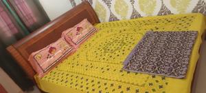 Una cama amarilla con dos bandejas encima. en Thiruvannamalai - 2BHK - Villa, en Tiruvannāmalai