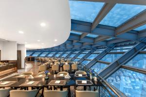 a dining room with tables and chairs and windows at Novotel Atlantis Shanghai - Enjoy our great-valued breakfast in our rooftop revolving restaurant with a stunning river view & utilize our FREE self-serviced laundry in Shanghai