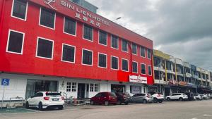 un edificio rojo con coches estacionados en un estacionamiento en SiN LiEN HOTEL en Keluang
