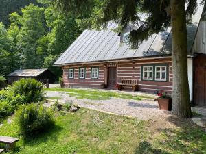 una cabaña de madera con un banco delante en Chalupa Šárka, en Dolni Dvur