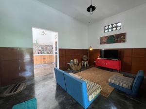 ein Wohnzimmer mit einer blauen Couch und einem Fernseher in der Unterkunft Homestay Jogja Rumah Obit By Simply Homy in Timuran