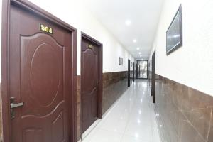 un couloir avec des portes brunes dans un bâtiment dans l'établissement Hotel Inderprasth, à Ābādpura