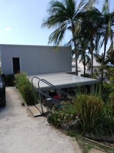 a building with a table and palm trees in a yard at Le Séchoir-maison de vacances atypique in Petite Île