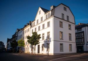 ein weißes Gebäude mit einem Baum davor in der Unterkunft YokoLou - Design-Apartments in Koblenz