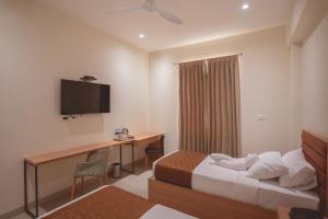 Habitación de hotel con cama, escritorio y TV. en HOTEL ACHYUT, en Tirupur