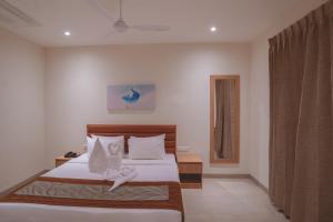 1 dormitorio con 1 cama con sábanas blancas y ventana en HOTEL ACHYUT, en Tirupur