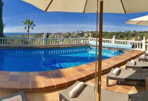 einen Pool mit Stühlen und einem Sonnenschirm in der Unterkunft Robis Moraira in Benissa