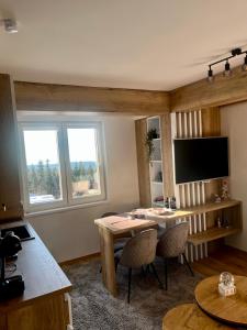 a living room with a table and a television at Pinewood apartment Jahorina in Jahorina