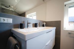 a bathroom with a white sink and a mirror at Ferienwohnung am Starnberger See in Feldafing +37 photos