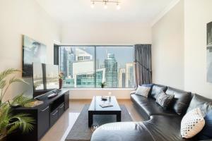 a living room with a leather couch and a large window at Manzil - 1BR Home in Dubai Marina with Marina View, Nr JBR Beach & Marina Mall in Dubai