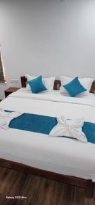 sypialnia z 2 łóżkami i białymi i niebieskimi poduszkami w obiekcie My Kingdom Munnar w mieście Munnar