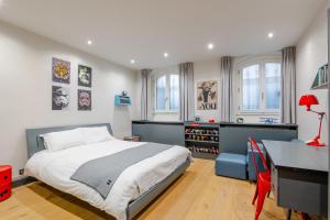 a bedroom with a bed and a desk and windows at Veeve - Blue Majesty in Paris