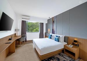 Una habitación de hotel con una cama, un escritorio y un televisor. en Oakwood Hotel & Apartments Taman Mini Jakarta, en Yakarta