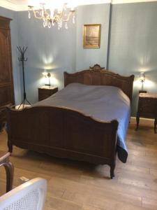Un dormitorio con una gran cama de madera con paredes azules en L'auberge en Baronville