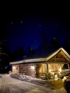 a log cabin with lights in the snow at night at Hillankukka in Äkäslompolo