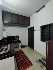 a kitchen with white walls and wooden cabinets at PEARL HUT home stay vythiri Wayanad in Vythiri