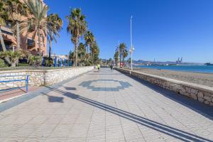マラガにあるMaritimo Apartment in Malaga by Solaga Holiday Homesのヤシの木と壁のあるビーチの歩道