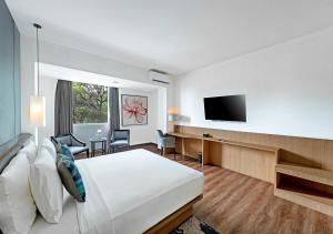 um quarto de hotel com uma cama e uma televisão de ecrã plano em Oakwood Hotel & Apartments Taman Mini Jakarta em Jacarta