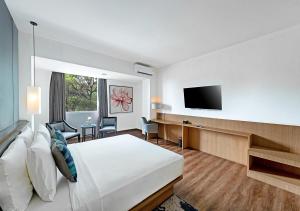 Oakwood Hotel & Apartments Taman Mini Jakarta في جاكرتا: غرفة فندقية بسرير وتلفزيون بشاشة مسطحة