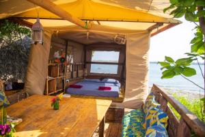 a tent with a wooden table in front of the ocean at Firefly Eco Retreat in Shimoni
