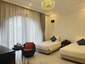 una habitación de hotel con 2 camas y una silla en WHITE HOTEL en Lạng Sơn