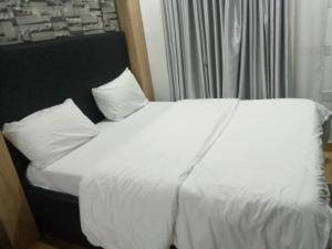 uma cama com lençóis brancos e almofadas ao lado de uma janela em Exclusive mansion lekki phase 1 em Ilado