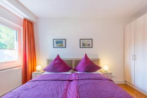 a bedroom with a purple bed with two lamps at Ferienwohnung "Blaues Haus" in Boltenhagen