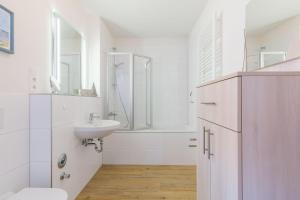 a white bathroom with a sink and a shower at Ferienwohnung "Blaues Haus" in Boltenhagen
