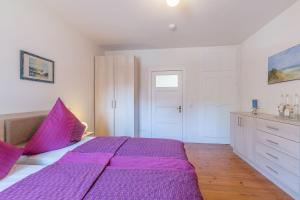a large purple bed in a white bedroom at Ferienwohnung "Blaues Haus" in Boltenhagen