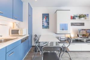 une cuisine avec des armoires bleues, une table et des chaises dans l'établissement Haffblick, Ferienwohnung 08, à Boltenhagen