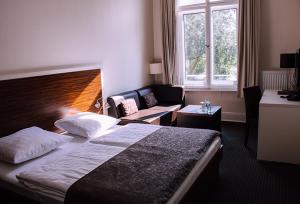 Habitación de hotel con cama y sofá en Hotel Excellent, en Lübeck