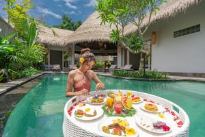 una mujer en una piscina con una mesa de comida en Brand new Luxury 3BR villa Ethnic Ubud #3 en Ubud