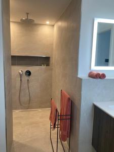 een badkamer met een douche, oranje handdoeken en een wastafel bij Alma - Art Luxus Modern Ambiente in Karlsruhe