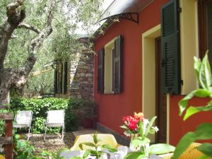 a house with a red and yellow wall and chairs at Agriturismo La Vigna in Chiusanico