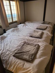 un letto bianco con tre cuscini sopra di Asagama House a Nozawa Onsen