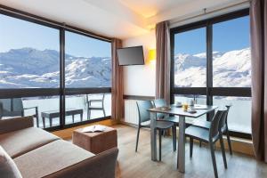 - un salon avec un canapé et une table avec des chaises dans l'établissement SOWELL RESIDENCES Pierre Blanche, aux Menuires