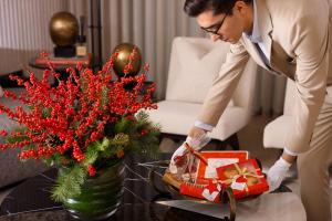 Un homme en costume qui organise un vase avec un cadeau dans l'établissement Vakko Hotel and Residence, à Istanbul