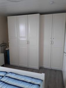 een witte slaapkamer met witte kasten en een bed bij Ankes Huus I in Tossenserdeich