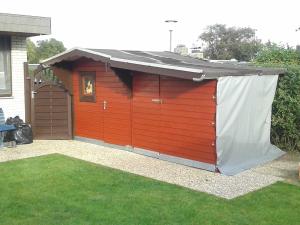 un garaje rojo con techo negro en Ankes Huus I, en Tossenserdeich