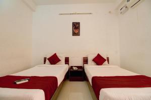 2 posti letto in una camera con lenzuola rosse e bianche di OYO The Mangrove Wood Residency a Chennai