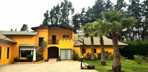 a yellow house with a palm tree in front of it at Casa Felice Altovalsol in La Serena