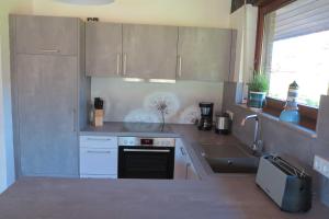 a kitchen with white cabinets and a stove and a sink at Ferienlandhaus Schäfer in Tossenserdeich