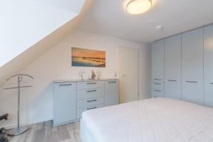 a white bedroom with a bed and a dresser at Villa Augusta, Ferienwohnung 10 in Boltenhagen