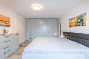 a bedroom with a white bed and white cabinets at Villa Augusta, Ferienwohnung 10 in Boltenhagen