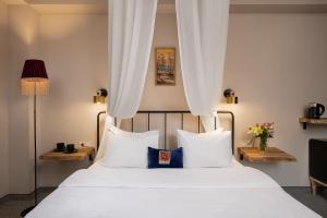 una camera da letto con letto, lenzuola e cuscini bianchi di Twentyone By Vintage Hotel Collections a Tbilisi City