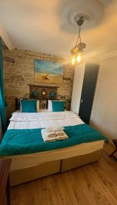 a bedroom with a large bed with blue pillows at Foca Antik Otel in Foça