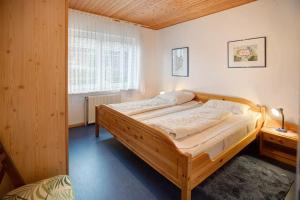 sypialnia z dużym drewnianym łóżkiem w pokoju w obiekcie Bungalow in Neßmersiel lädt mit seiner Terrasse und weiteren Annehmlichkeiten zum erholsamen Urlaub ein. w mieście Neßmersiel