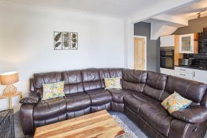 a brown leather couch in a living room with a table at Host & Stay - Seagull Cottage in Bridlington