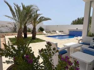 um pátio com palmeiras e uma piscina em Villa oasis em Arkou