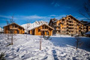 un lodge dans la neige avec des arbres au premier plan dans l'établissement Chalet 6 / 8 personnes Super Dévoluy, à Superdevoluy